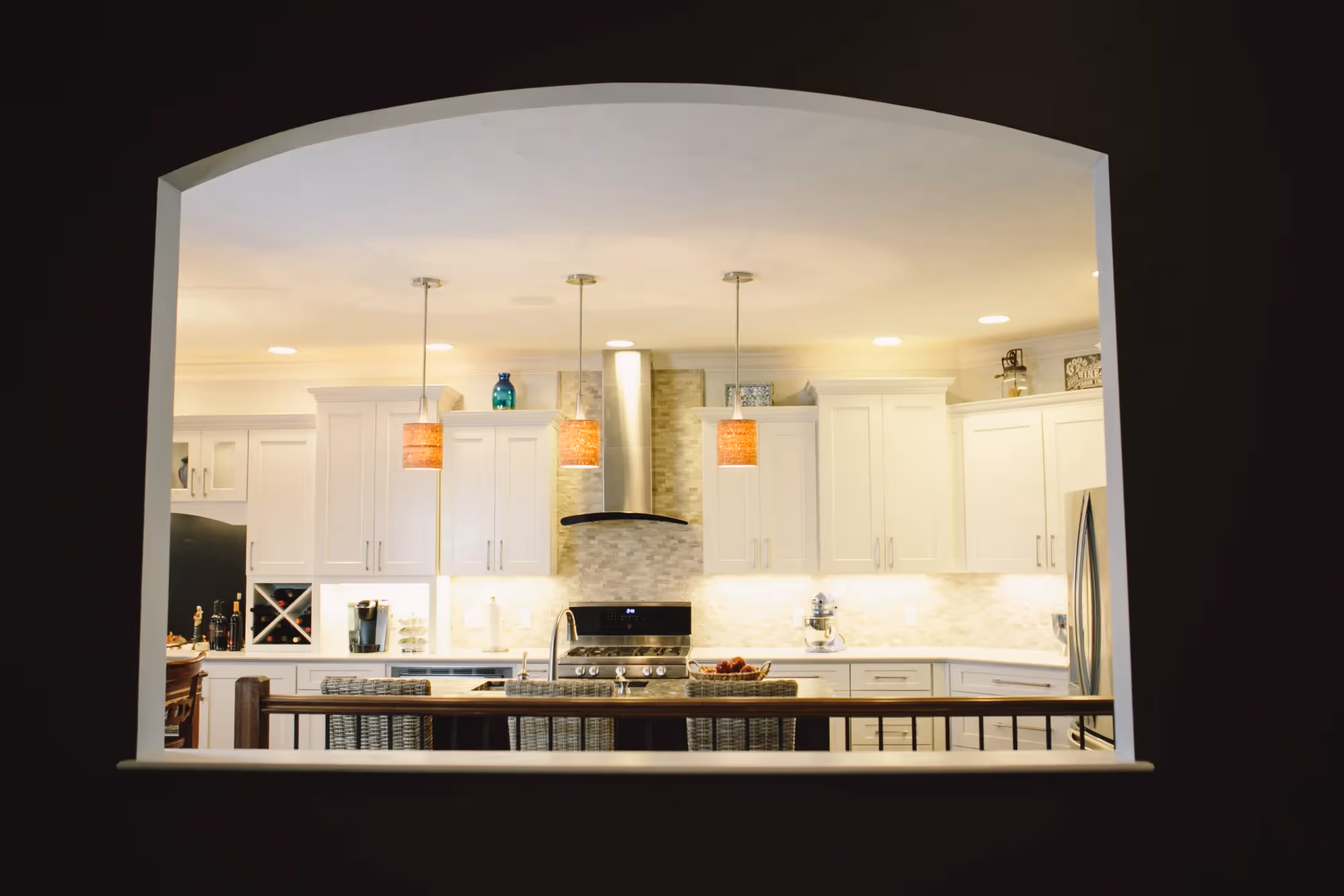 Spacious white kitchen with high ceiling and bar seating.