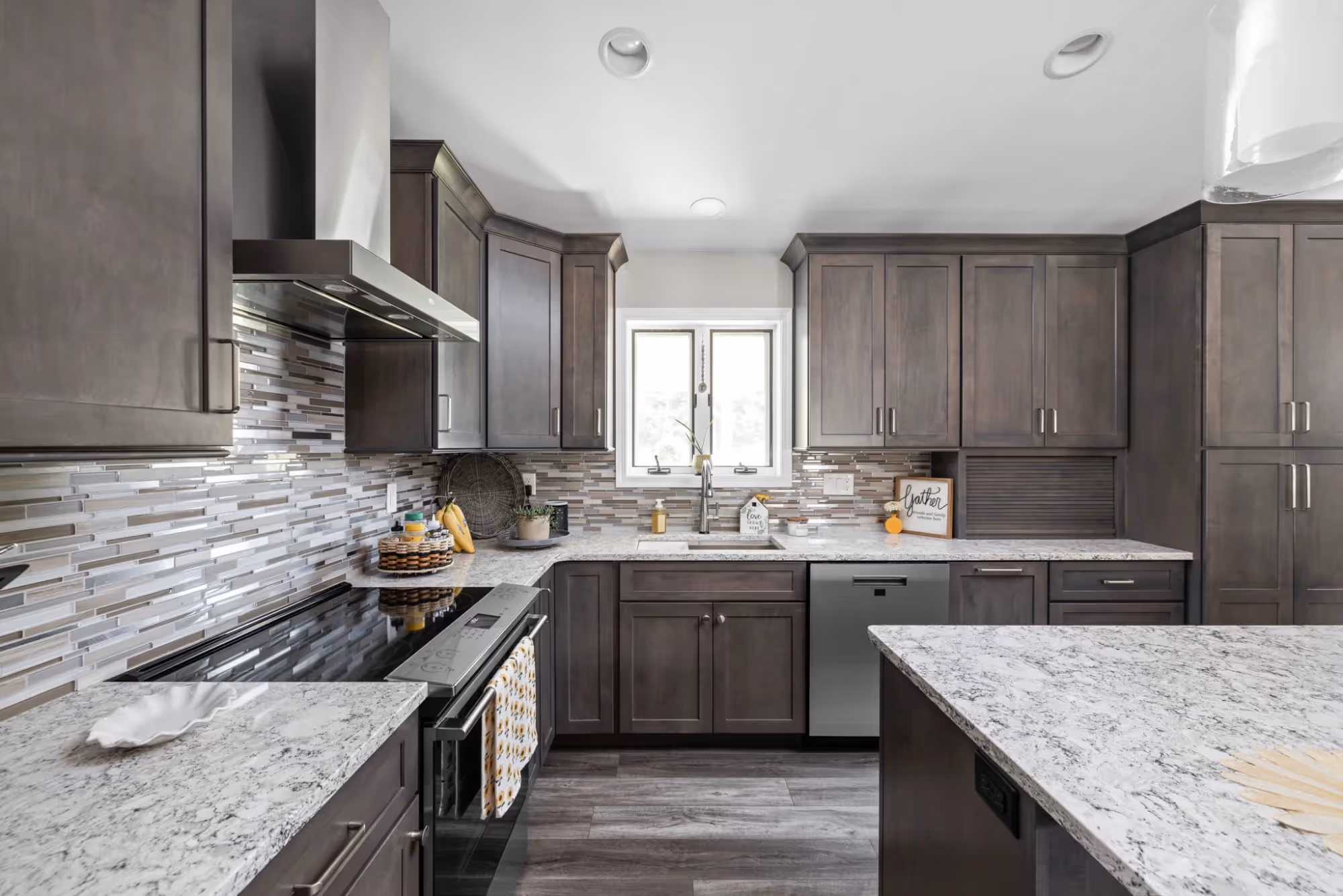 Contemporary kitchen with stainless range hood and marble counters