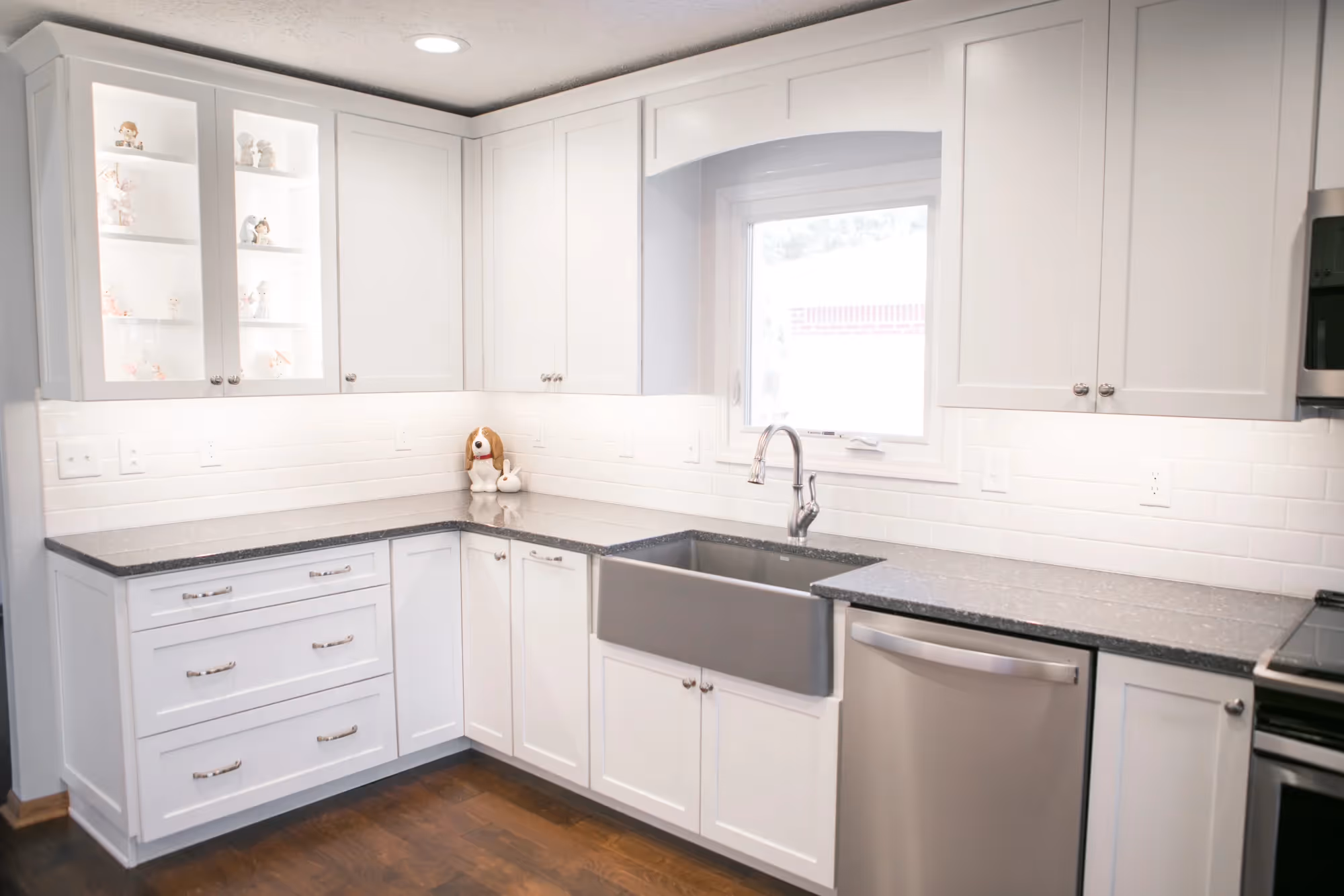 Corner view of a white kitchen with large window and built-in sink.