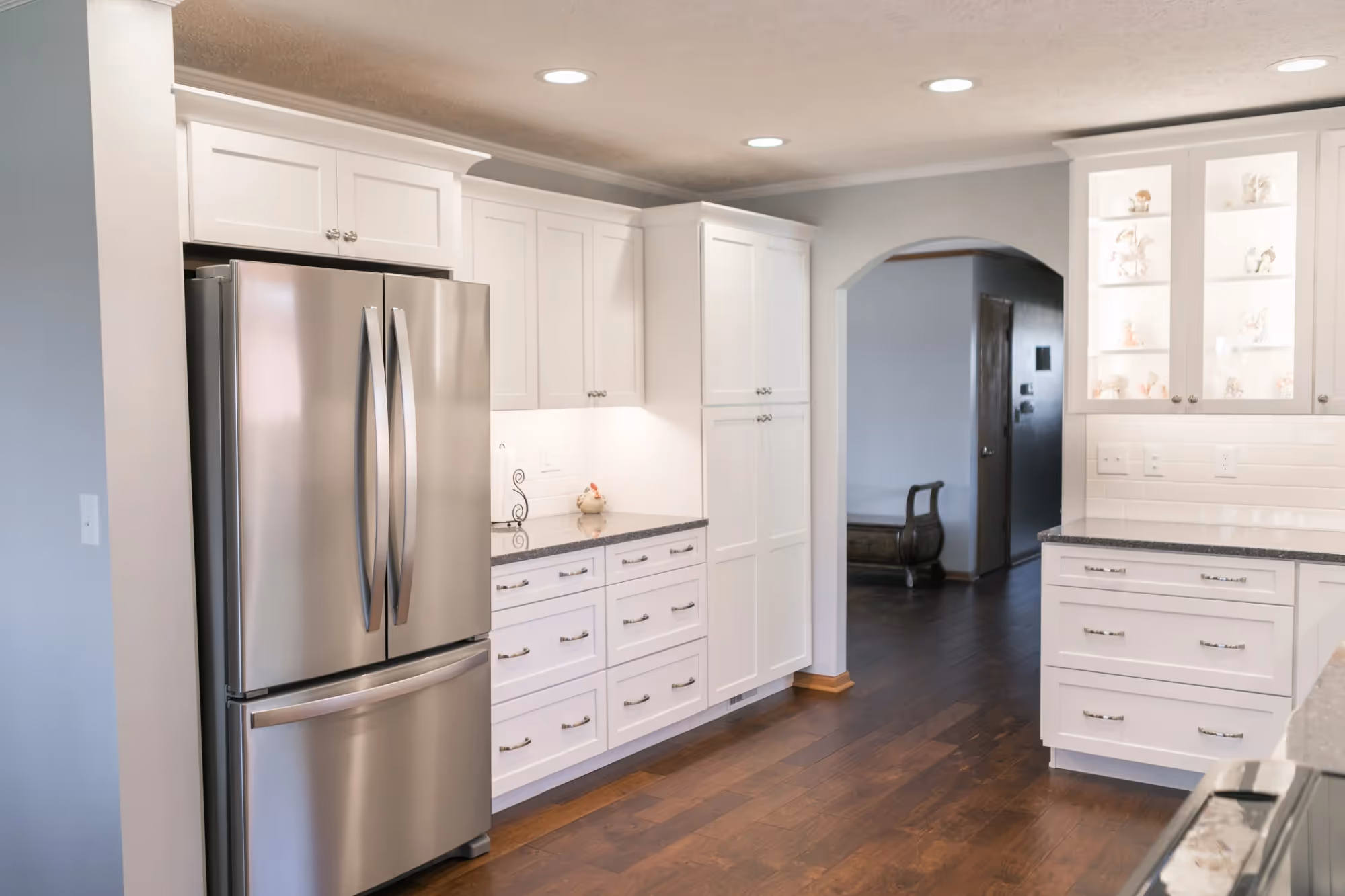Bright white kitchen with stainless steel refrigerator and island