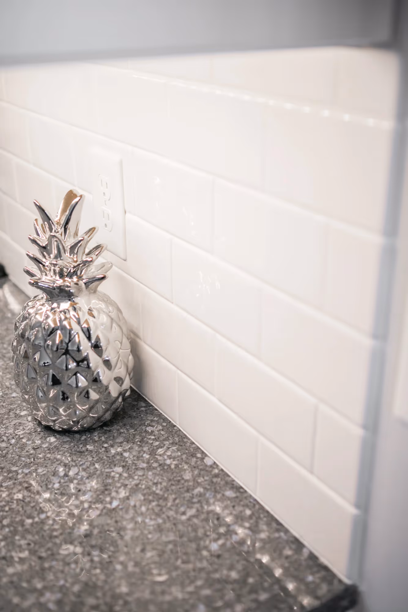 Decorative pineapple on kitchen counter by white tile backsplash