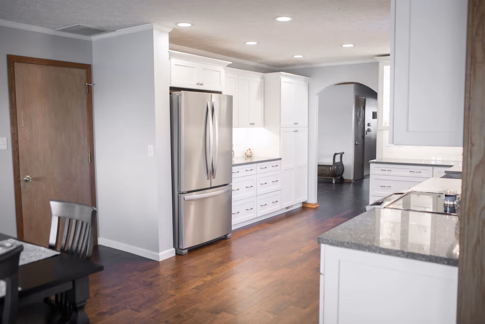 Modern kitchen with stainless steel appliances and wooden flooring.