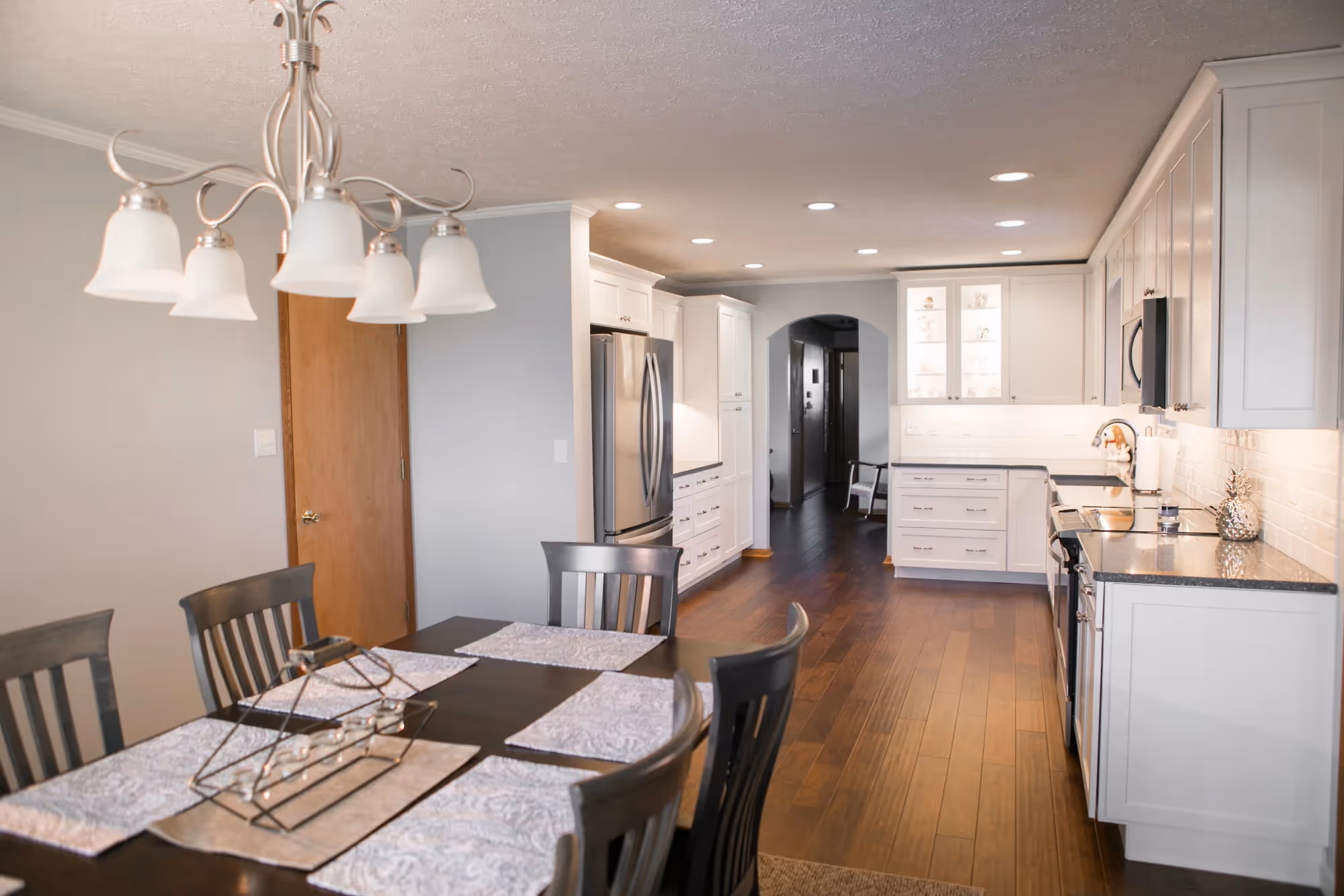Modern dining area beside open kitchen with white cabinets