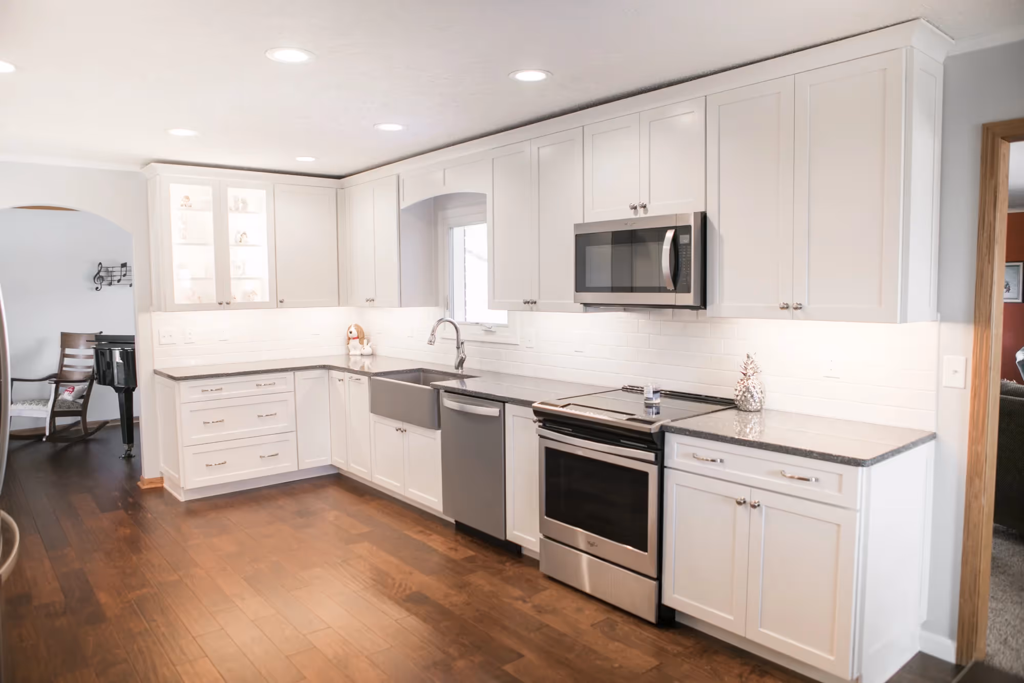 White kitchen with stainless range, microwave, and granite island