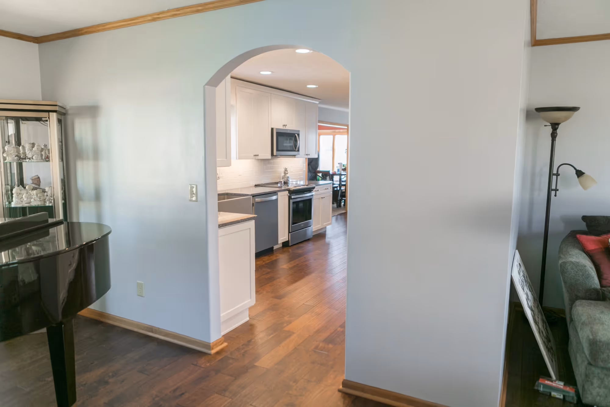 Open kitchen and living area with arched entry and hardwood floors.