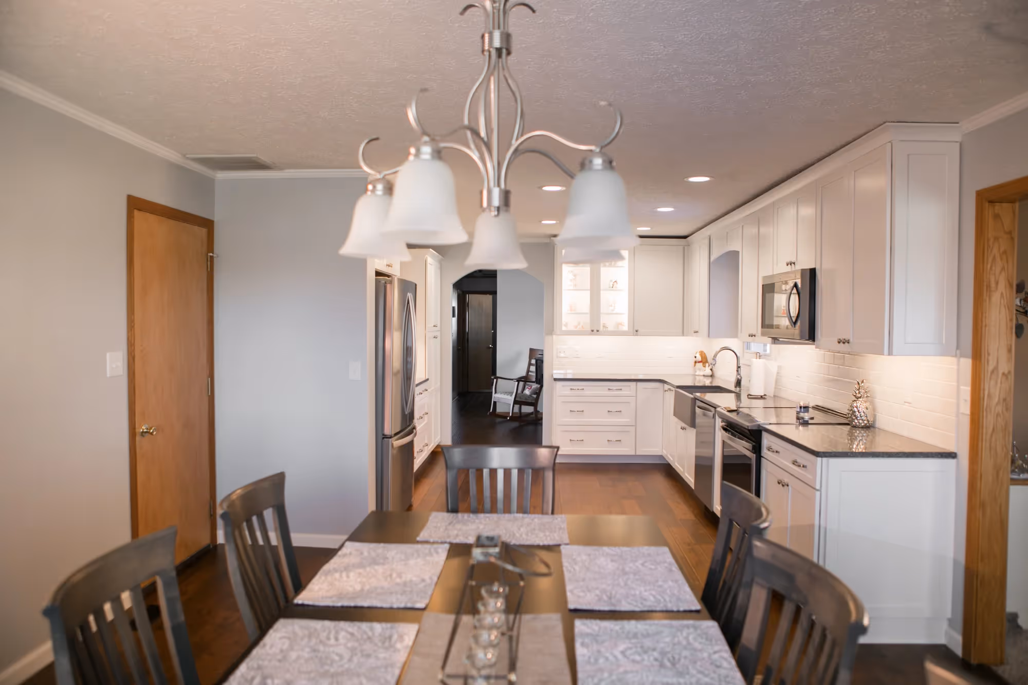 Dining table beside kitchen with island and pendant lights