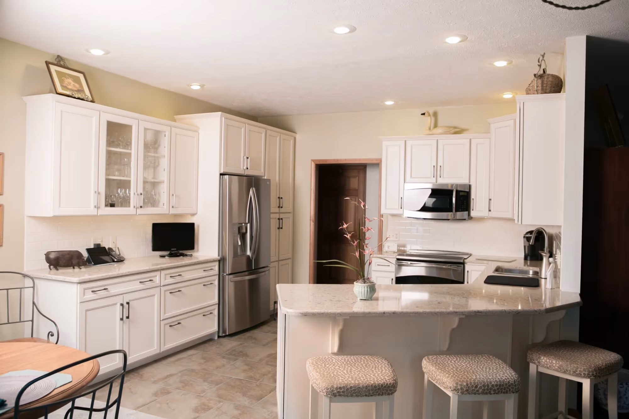 Spacious kitchen with white cabinetry, island, and modern appliances.