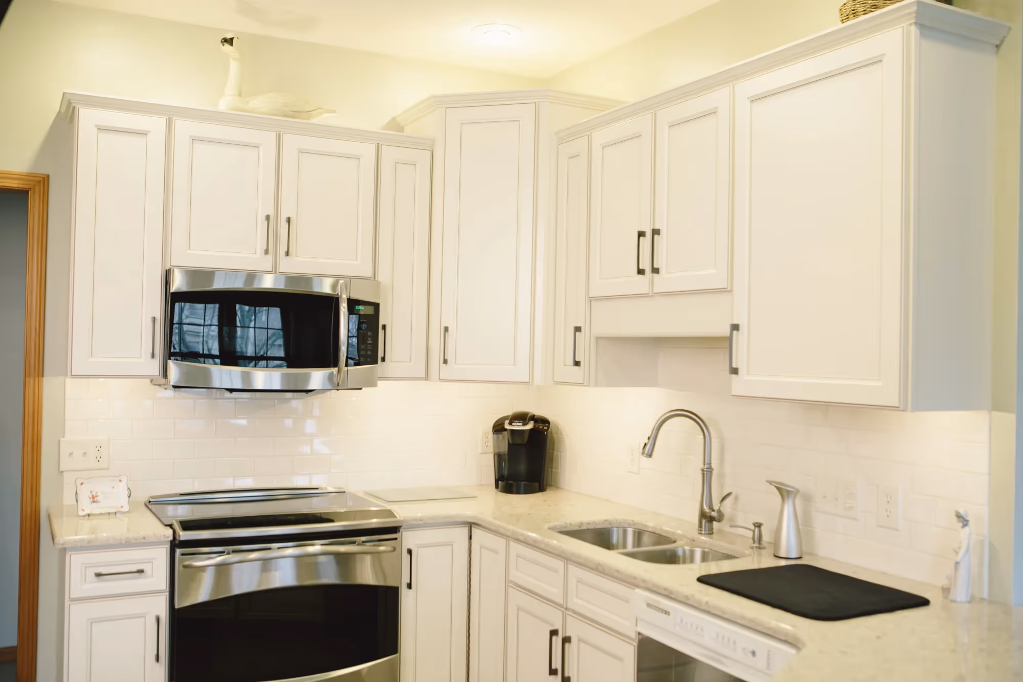 Bright kitchen with white cabinets and stainless steel appliances.