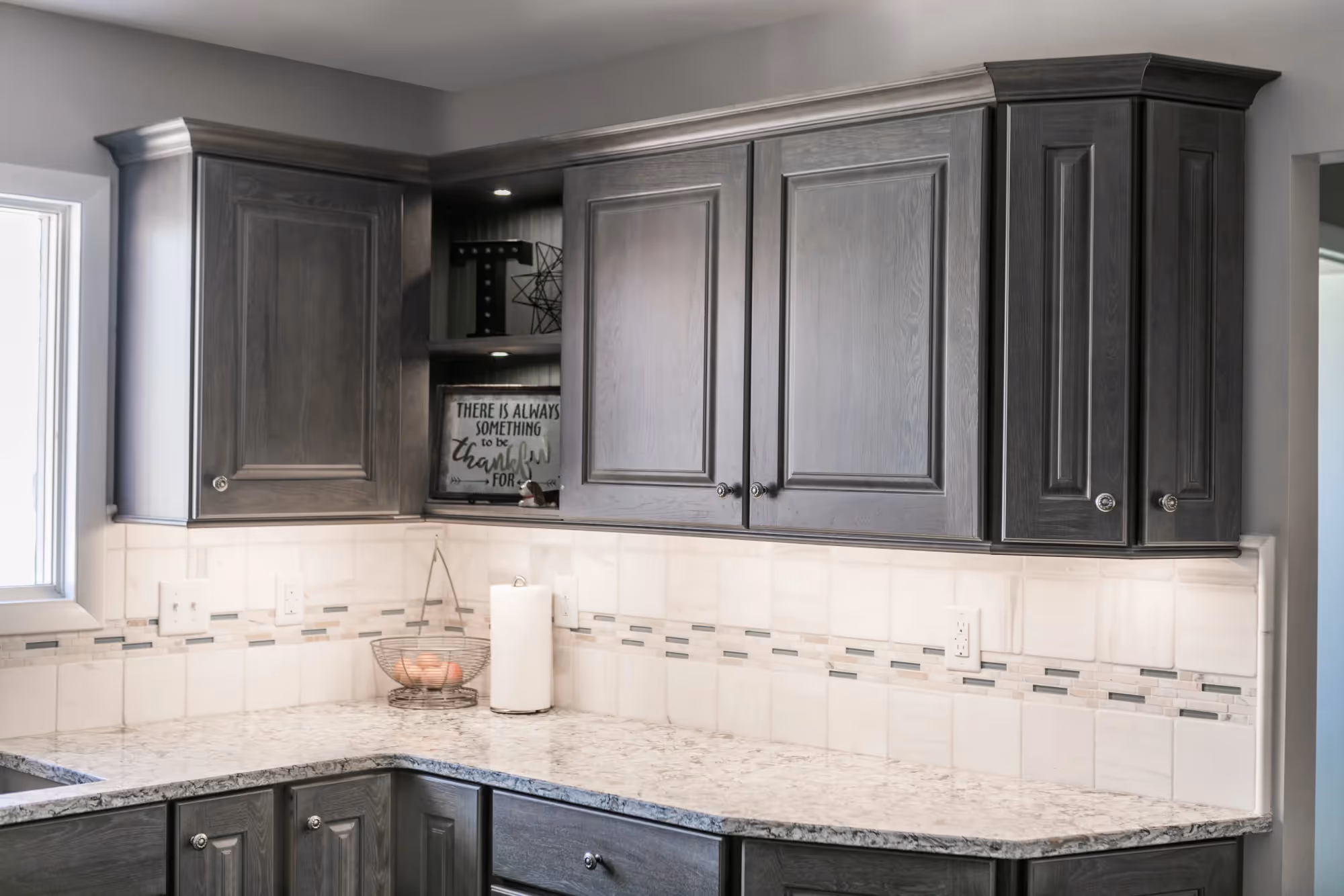Gray kitchen with white marble countertops and decorative backsplash tiles.