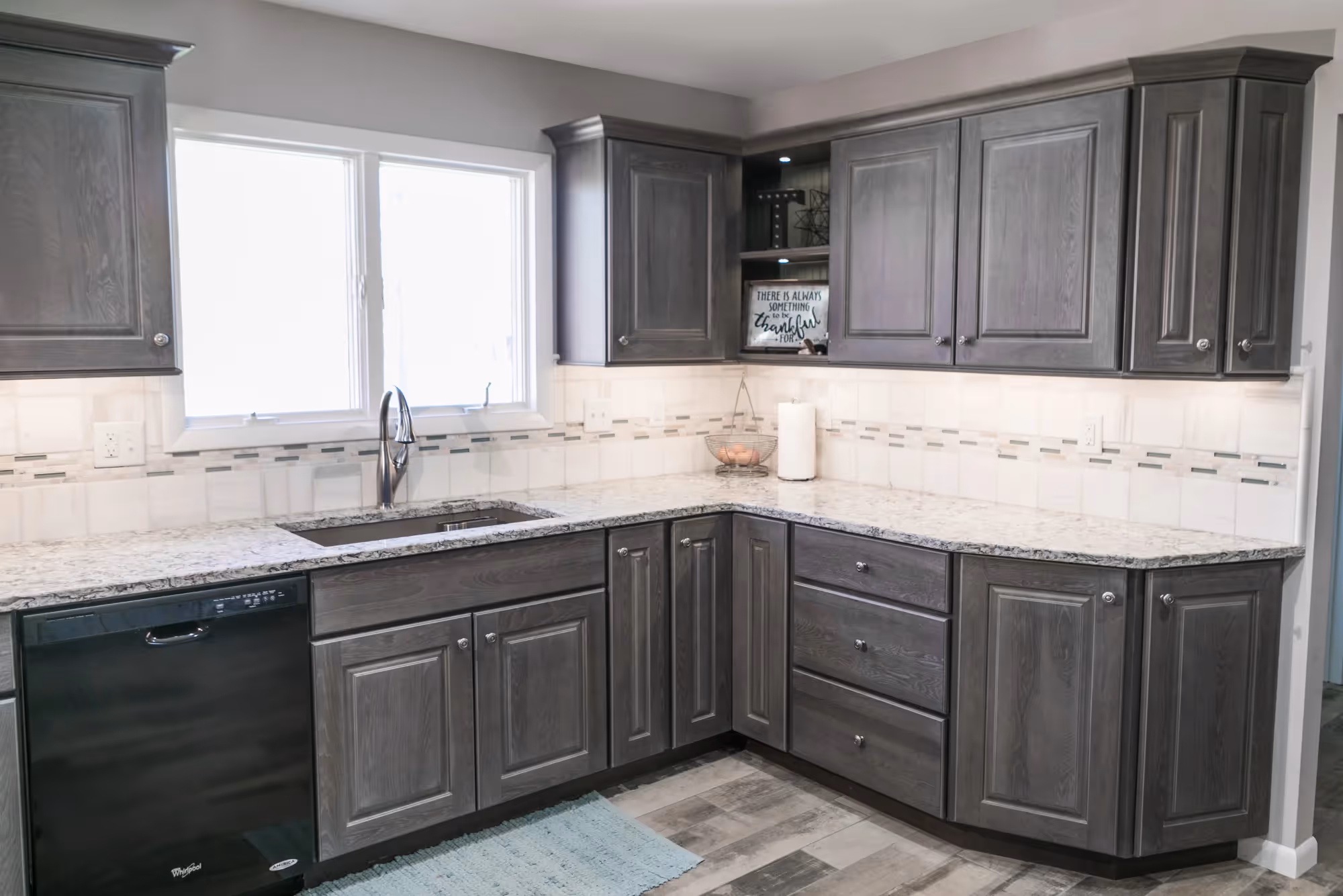 Modern kitchen with gray cabinets and marble countertops.