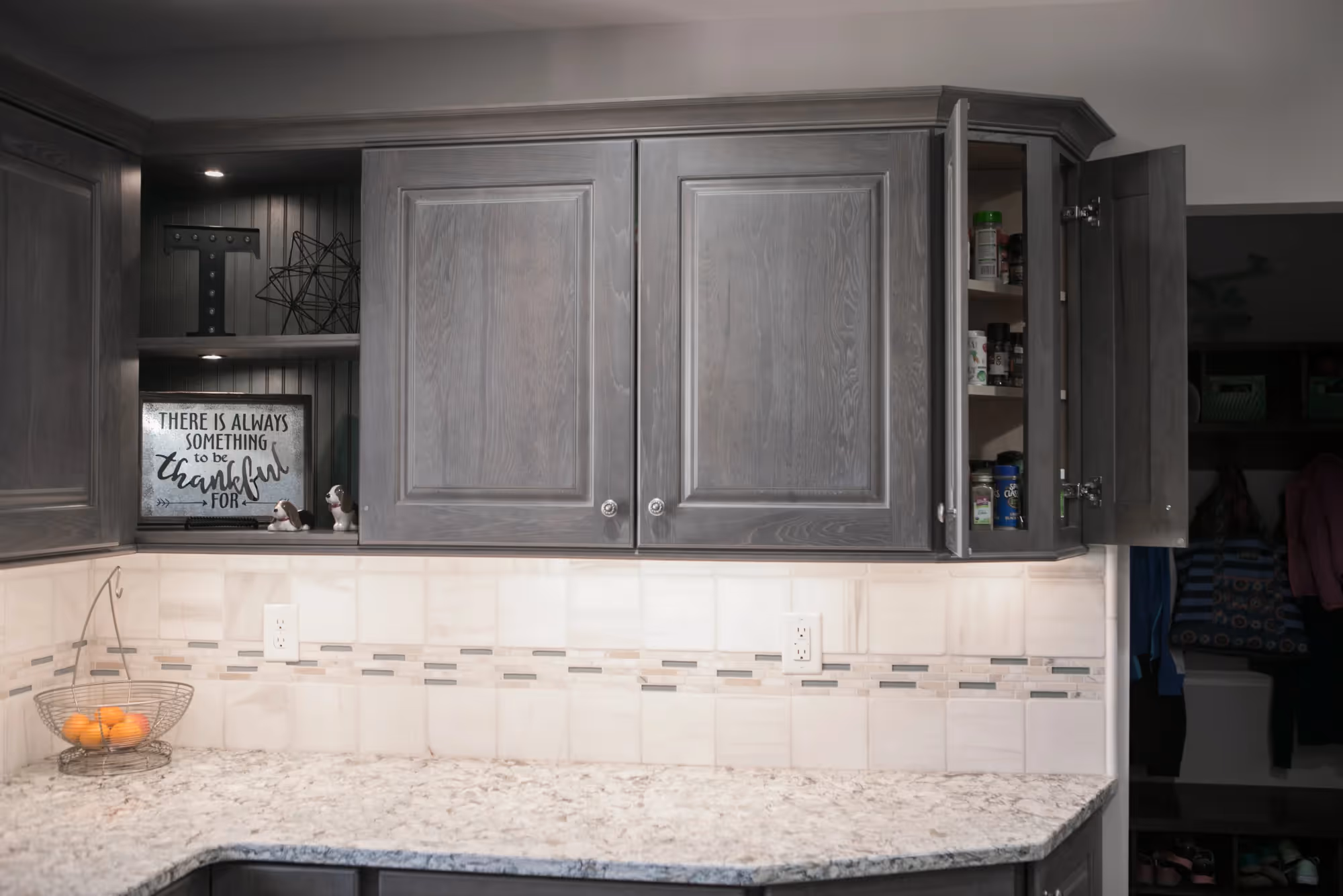 Close-up of gray kitchen cabinets with white marble backsplash.