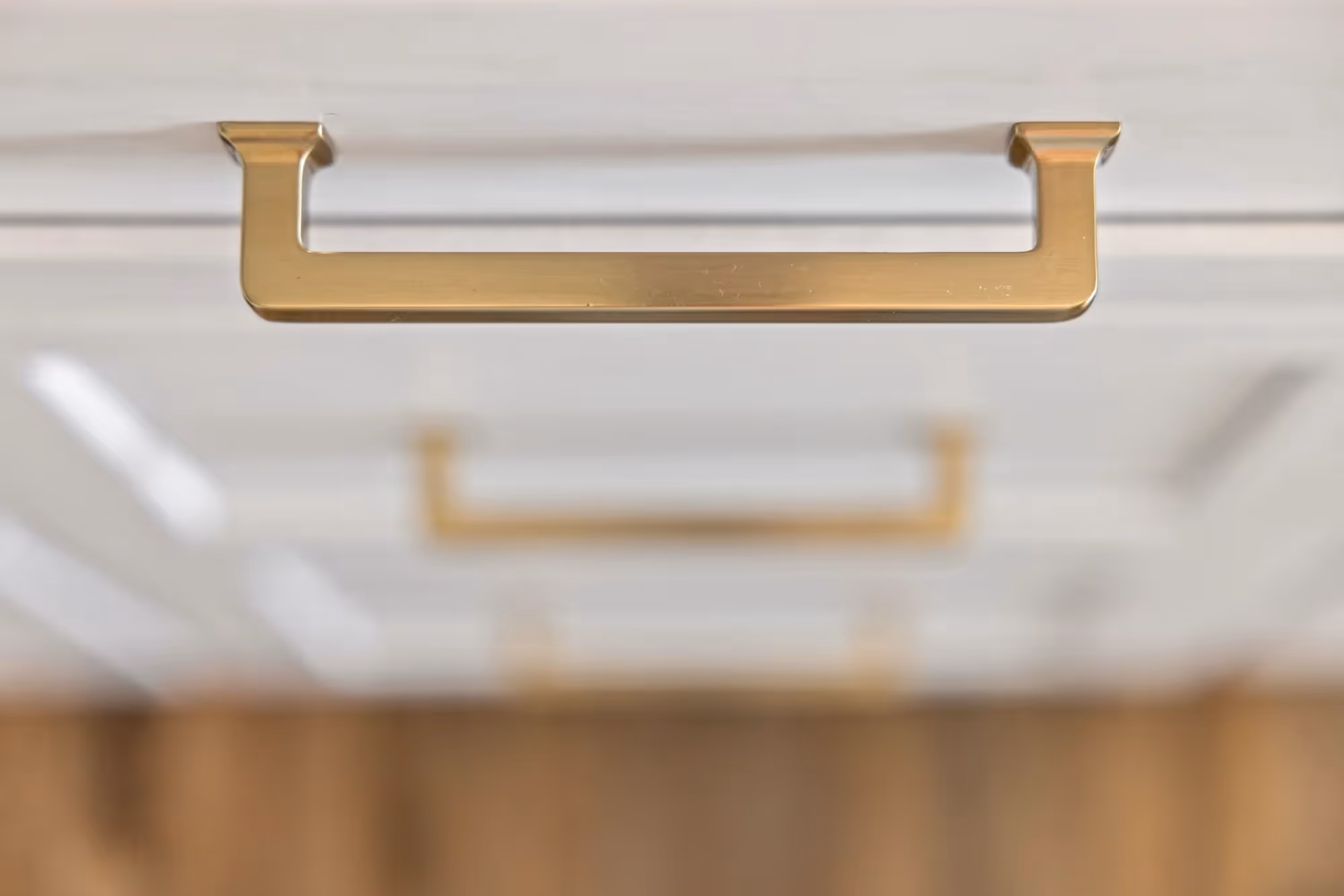 Close-up of brass drawer pull on white cabinet