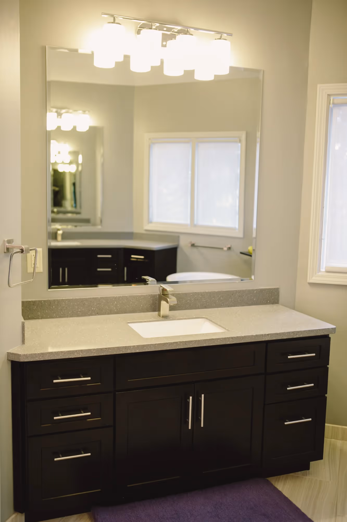 Bathroom vanity with dark cabinets and large mirror.