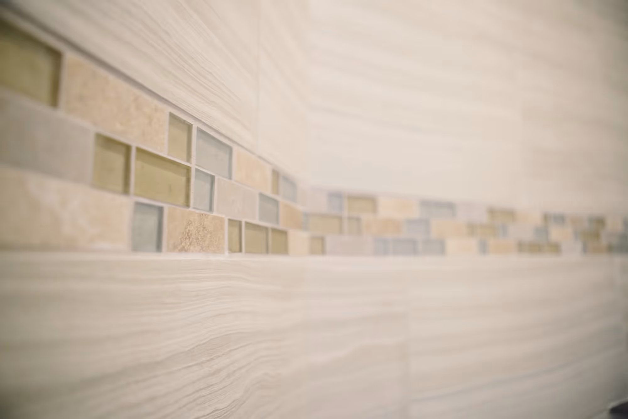 Close-up of beige tiled shower wall with decorative accent strip