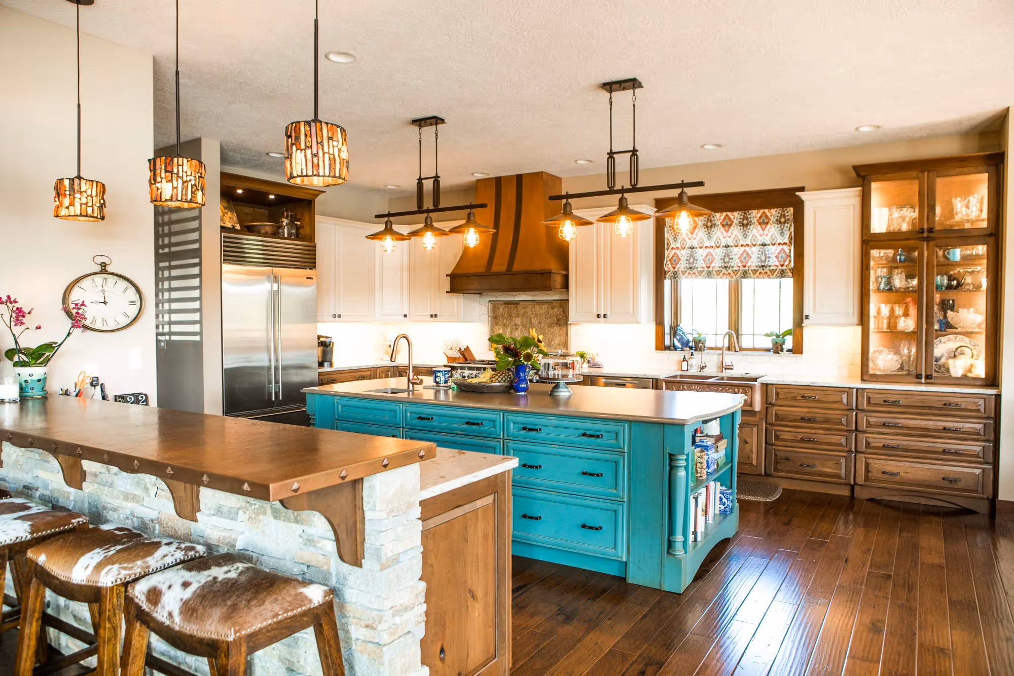 Open-concept kitchen with turquoise island and pendant lights