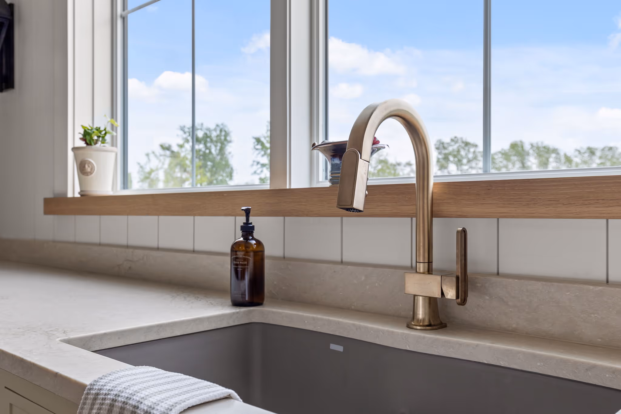 Modern kitchen sink with brass faucet by window