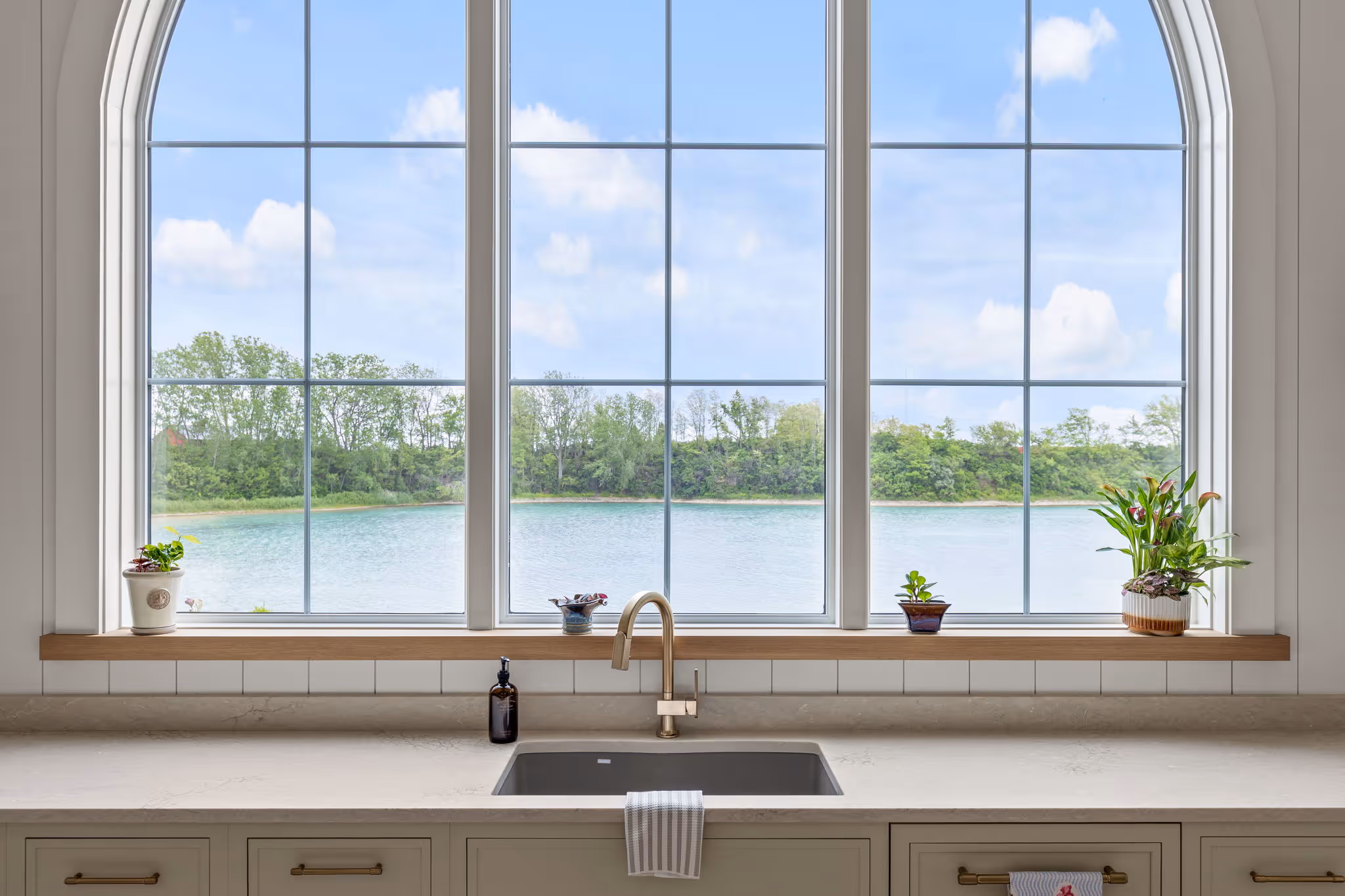 Kitchen sink under large arched window with lake view