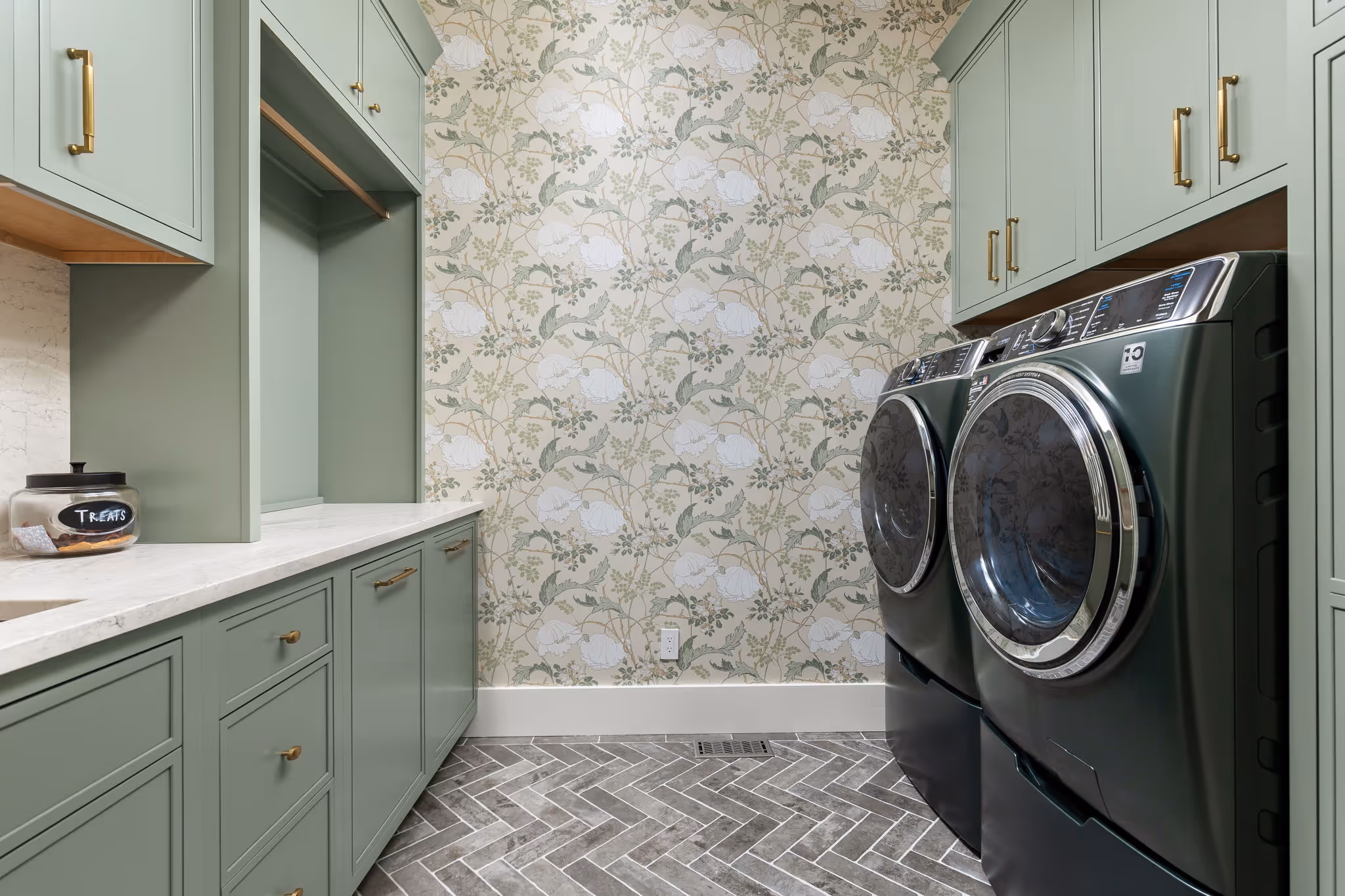 Laundry area with washer and dryer beside green cabinets
