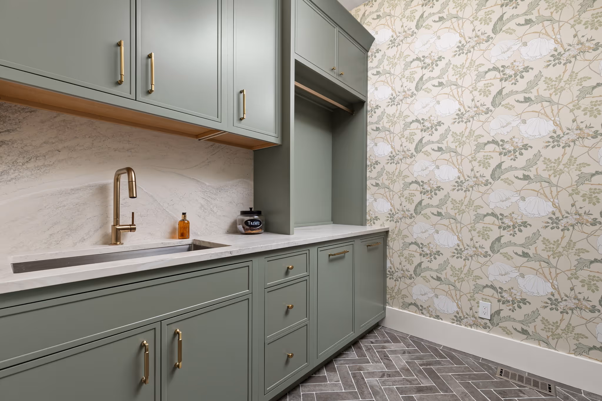Green kitchen cabinets with marble backsplash and brass hardware