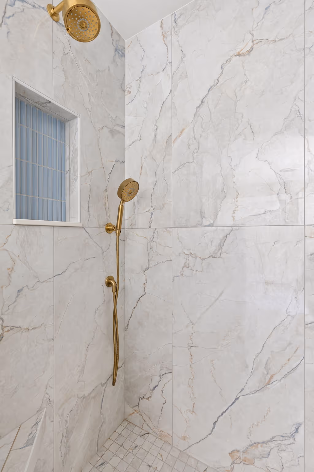 Marble shower with glass door and brass fixtures