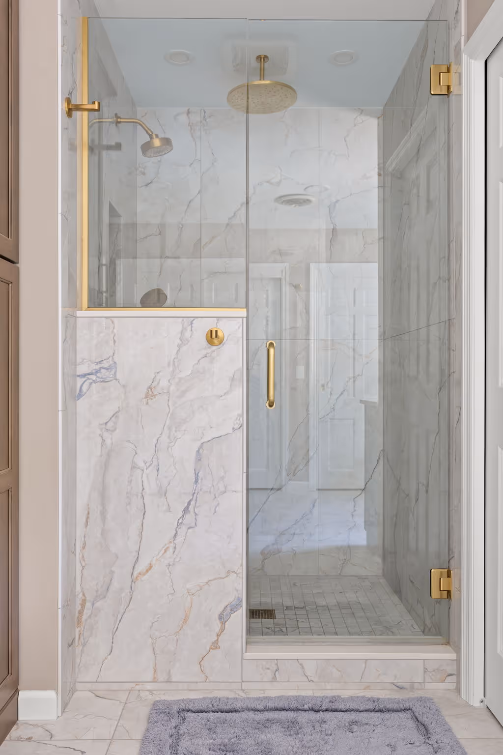 Marble shower with glass door and brass fixtures