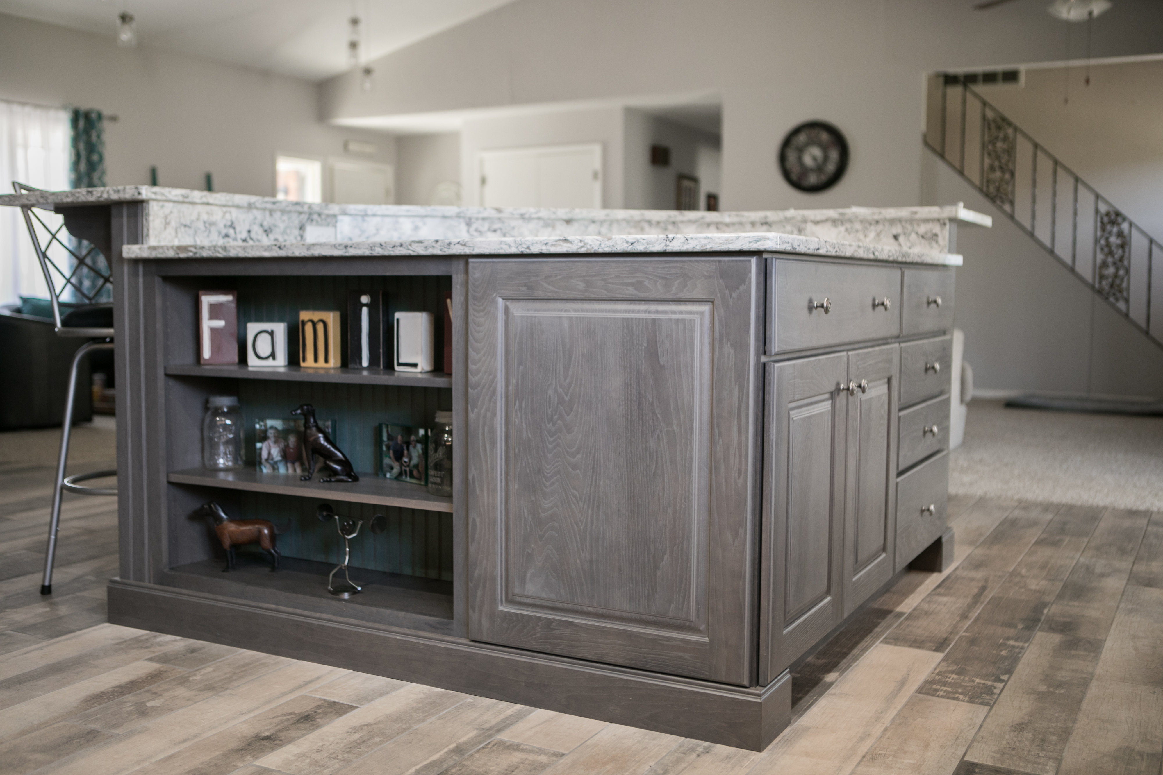 Kitchen island with gray cabinetry and white marble countertop in open layout.