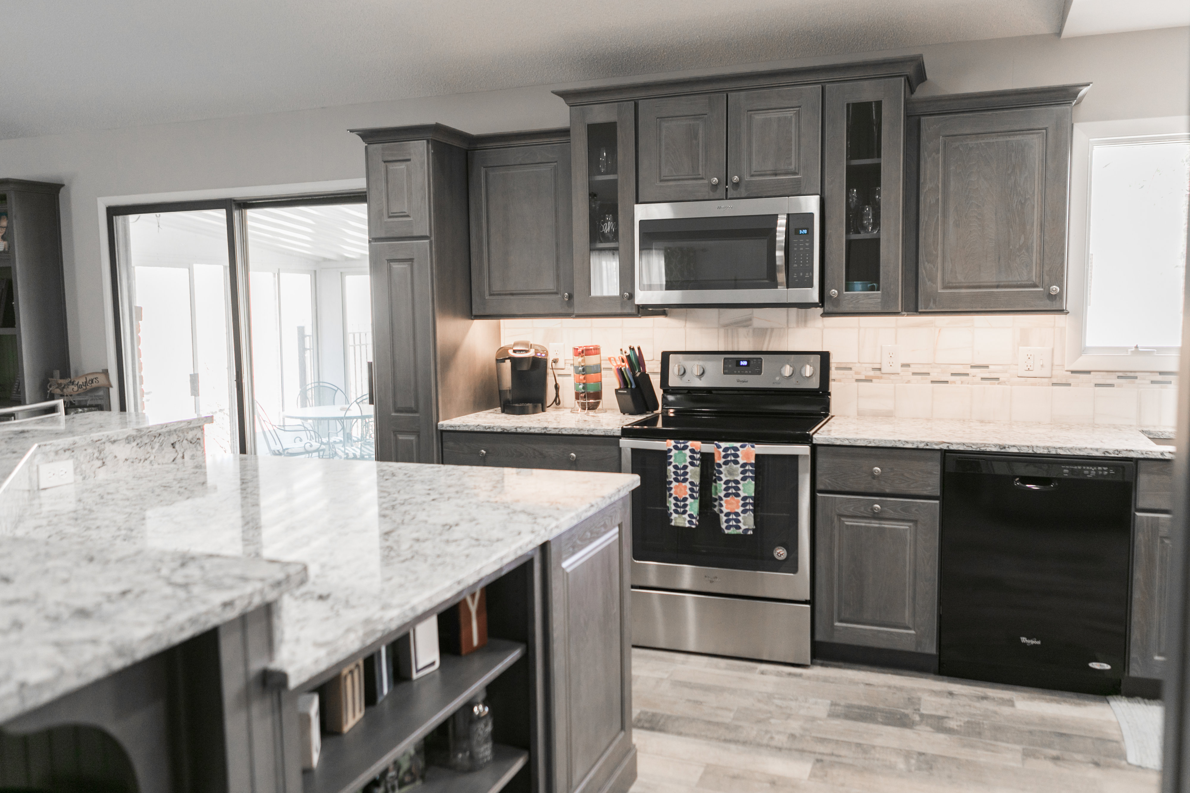 Modern kitchen with gray cabinets, marble countertops, and stainless steel appliances.