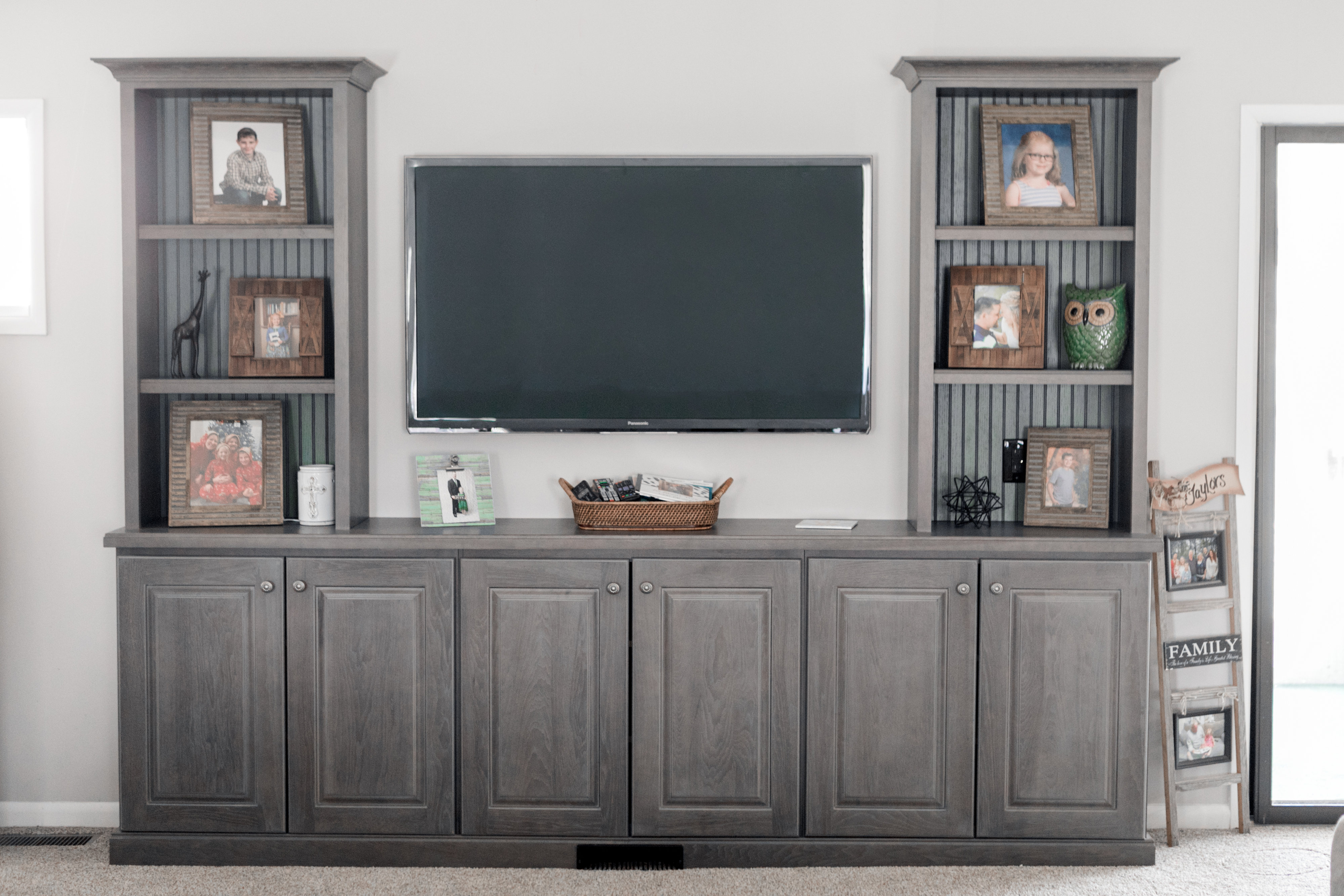 Living room with built-in TV cabinet and gray storage units.