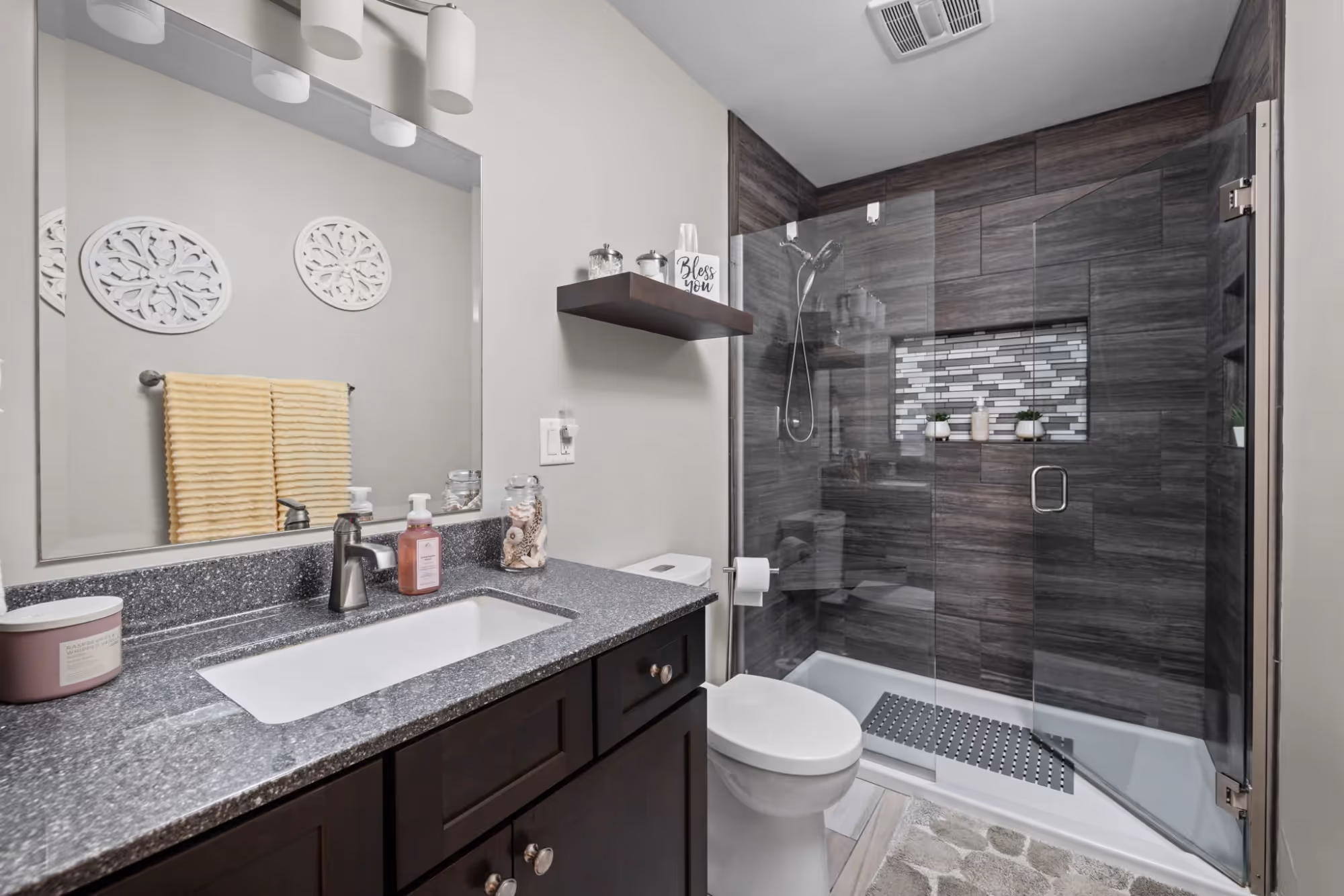 Bathroom with vanity counter and walk-in shower with dark tile