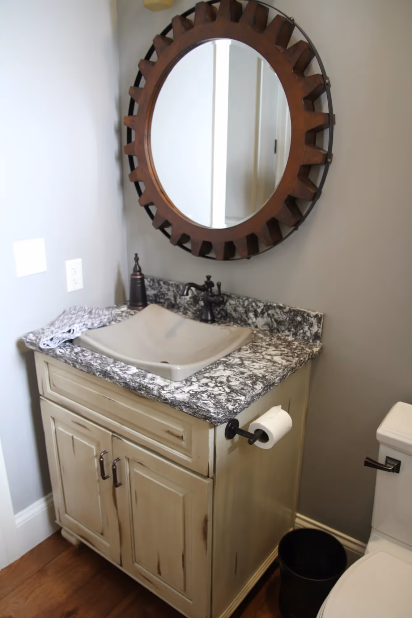 Bathroom with a vanity, round mirror, and decorative accents.