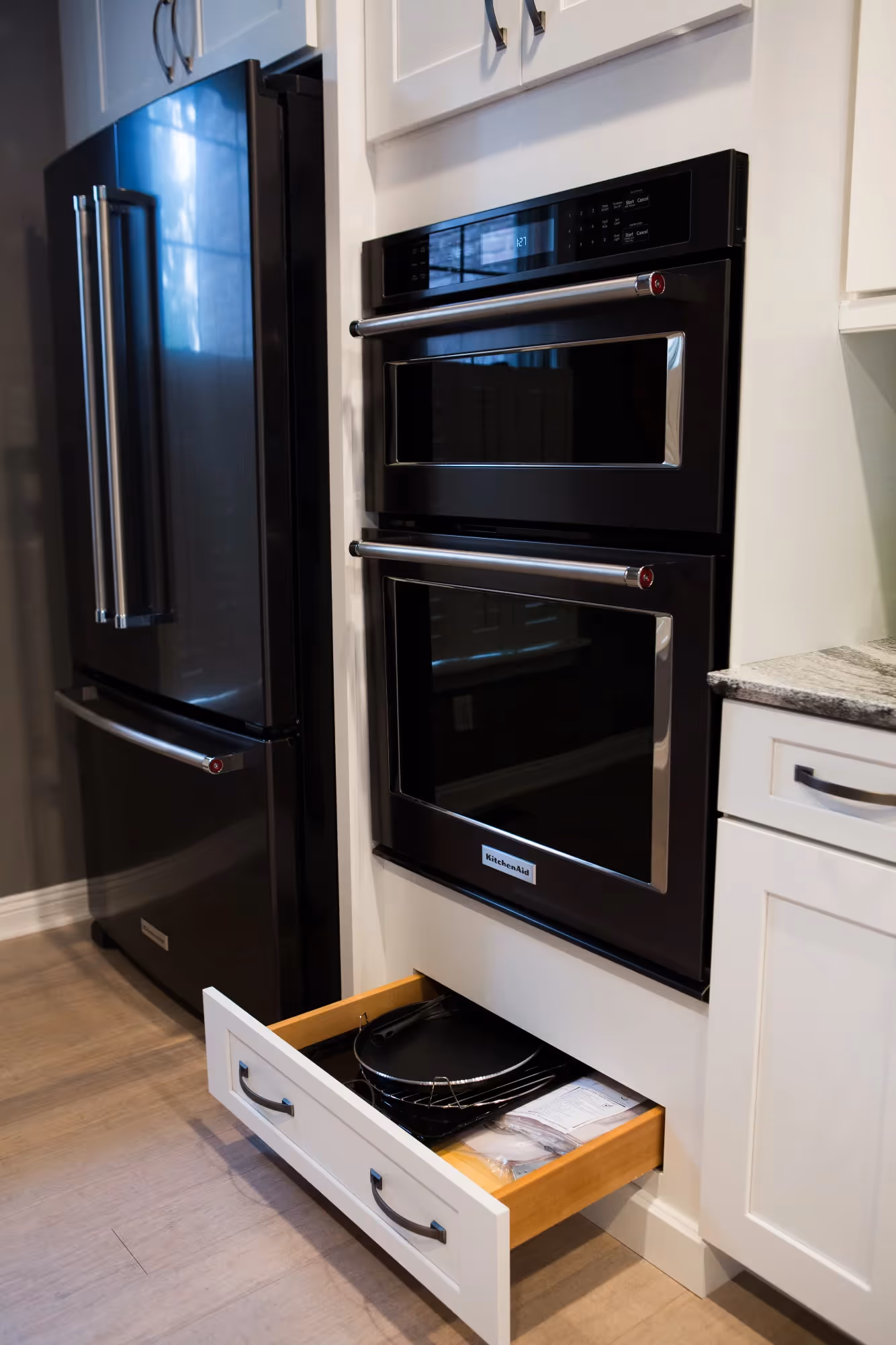 Drawer open beside black refrigerator in kitchen
