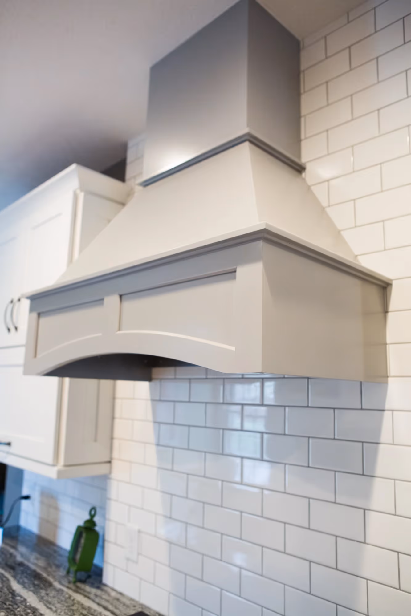 White kitchen range hood with light blue tile backsplash