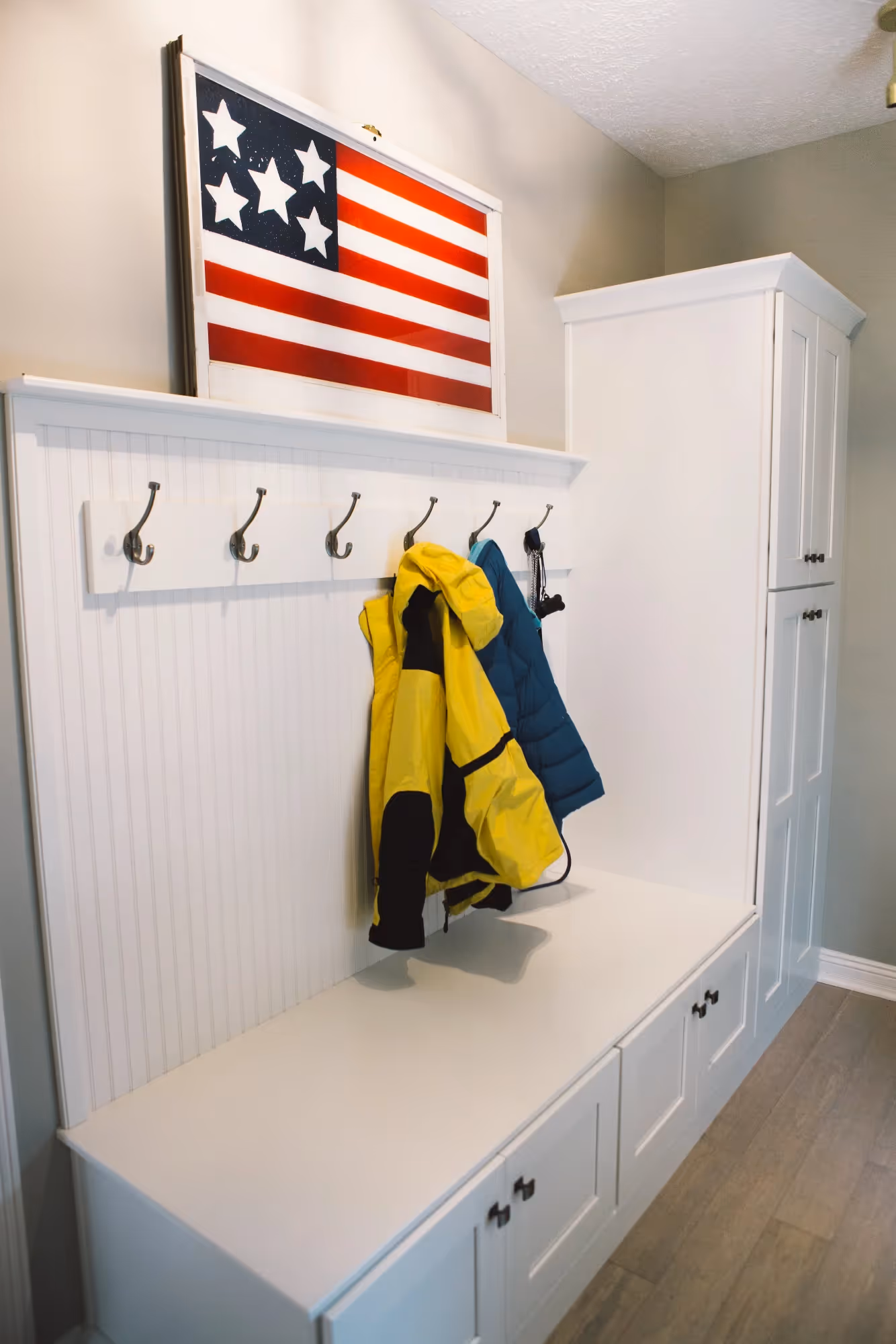Small American flag and hanging towels on wall hooks