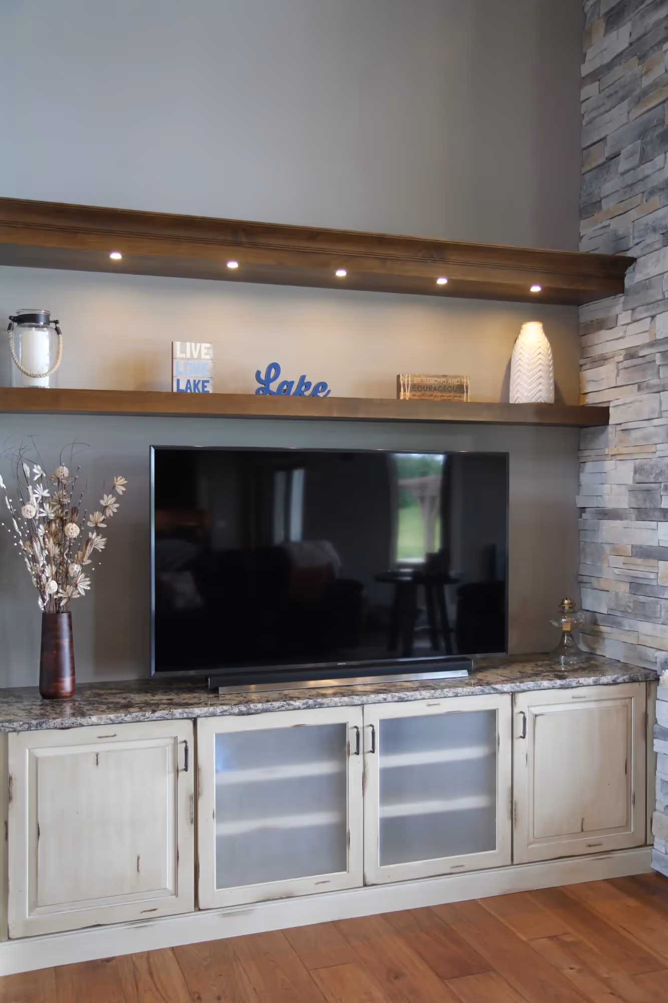 White entertainment unit with large TV and storage cabinets.