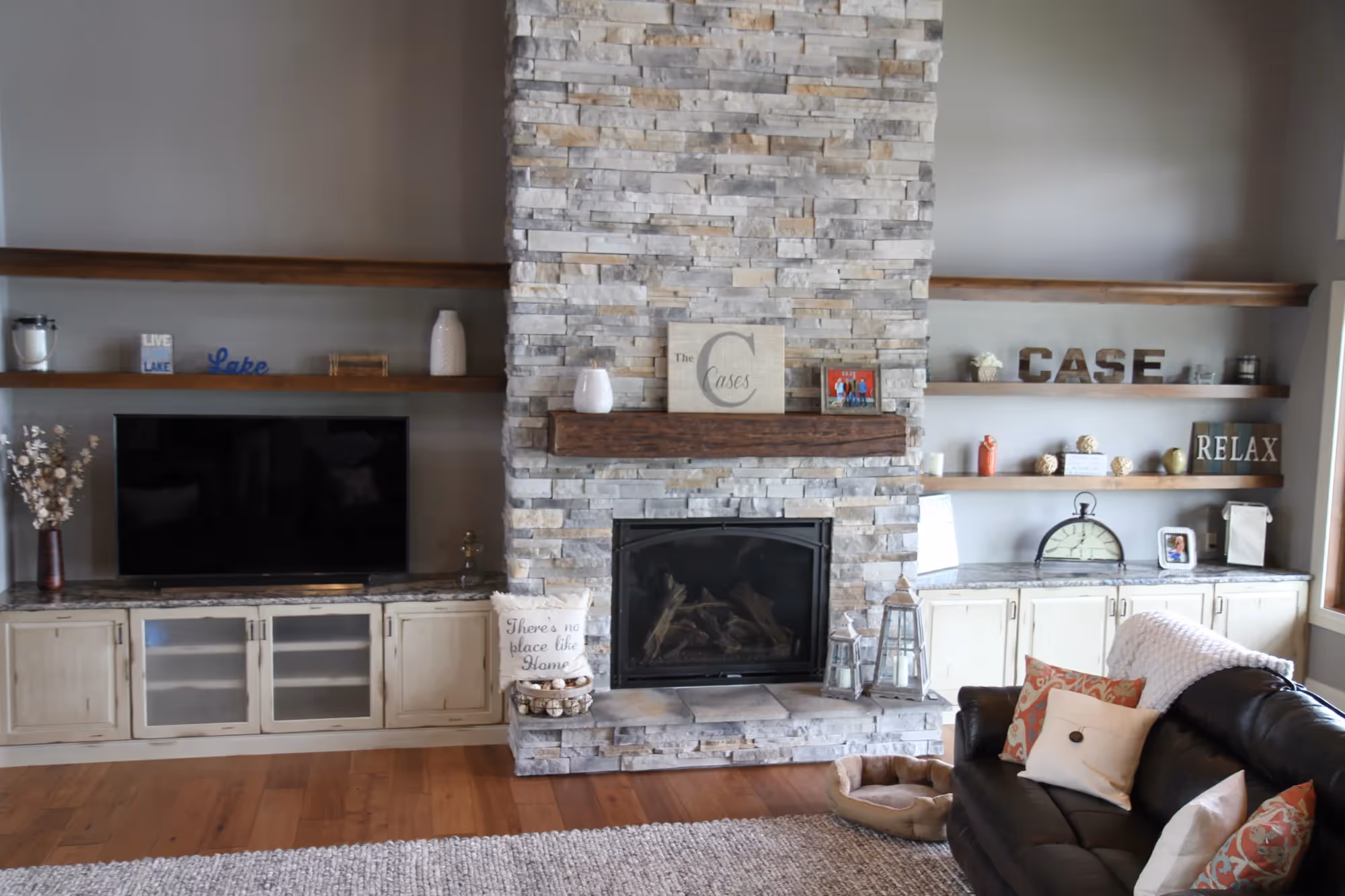 Stone fireplace with white built-in cabinets and shelves.