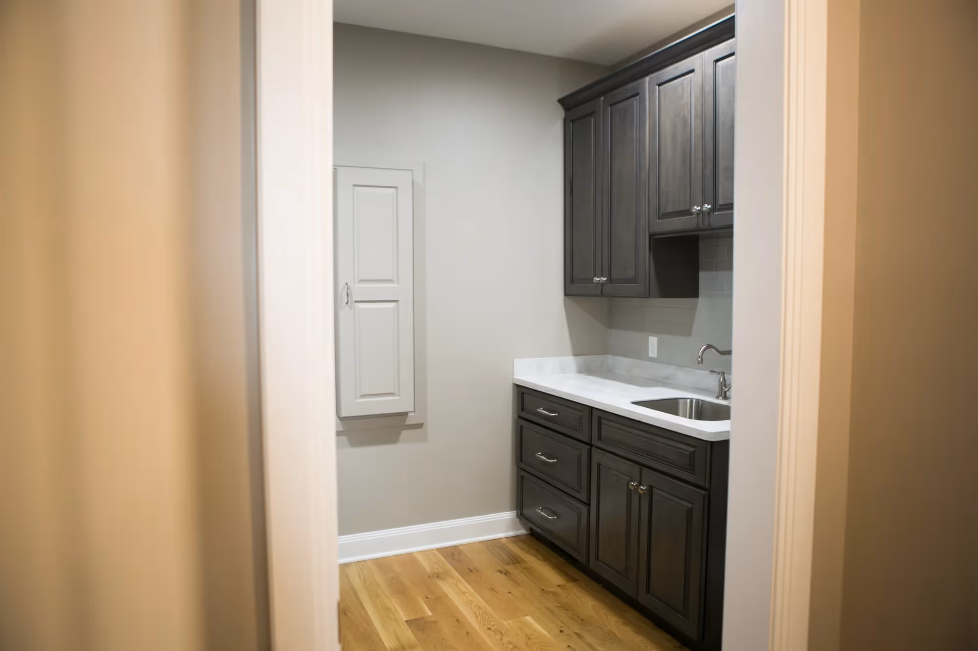 Narrow galley kitchen with dark cabinets and wood flooring