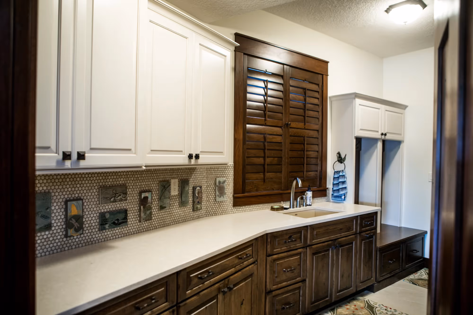Long kitchen with white cabinets and stone countertops