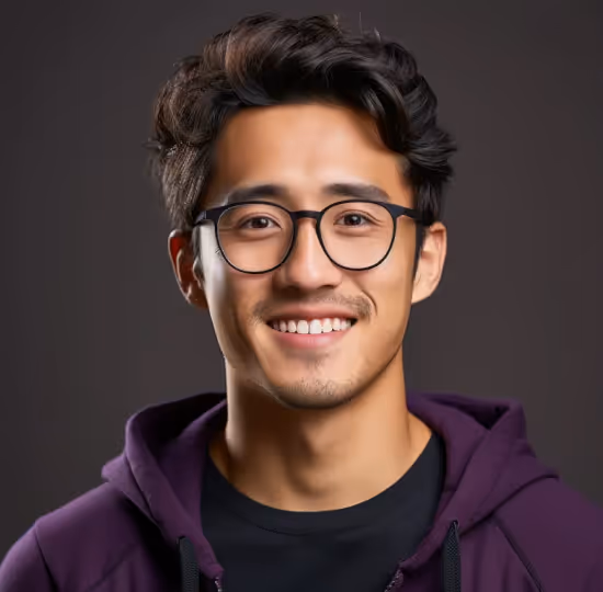 Smiling young man with black glasses and wavy hair wearing a purple hoodie against a dark background.