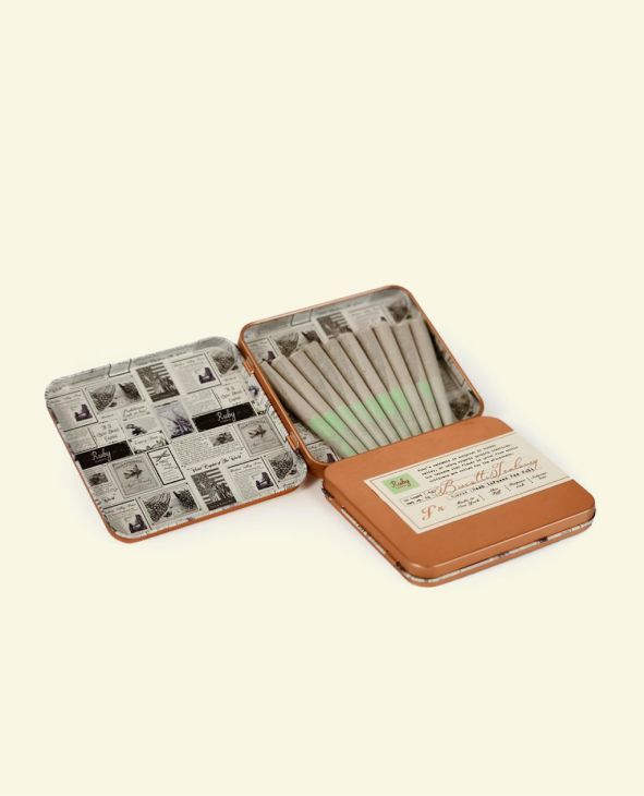 Open tin box showing nine neatly arranged pre-rolled joints with printed labels inside the lid.