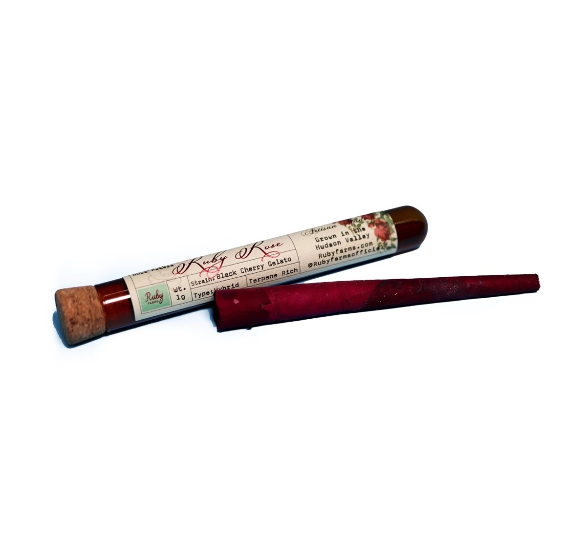 Glass tube labeled Ruby Rose strain and a deep red rolled item next to it on a white background.