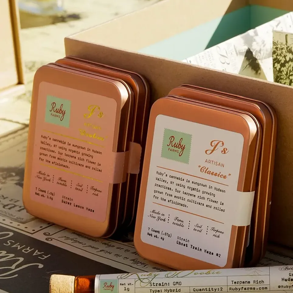 Copper tins of Ruby Farms cannabis products labeled 'Classic' and 'P's', with detailed strain info.