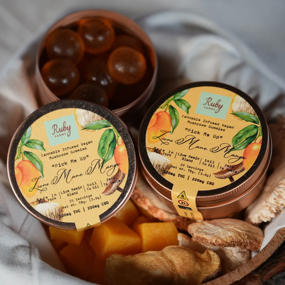 Two containers of Ruby Farms cannabis-infused vegan mushroom gummies with mango theme and dried mushrooms around.