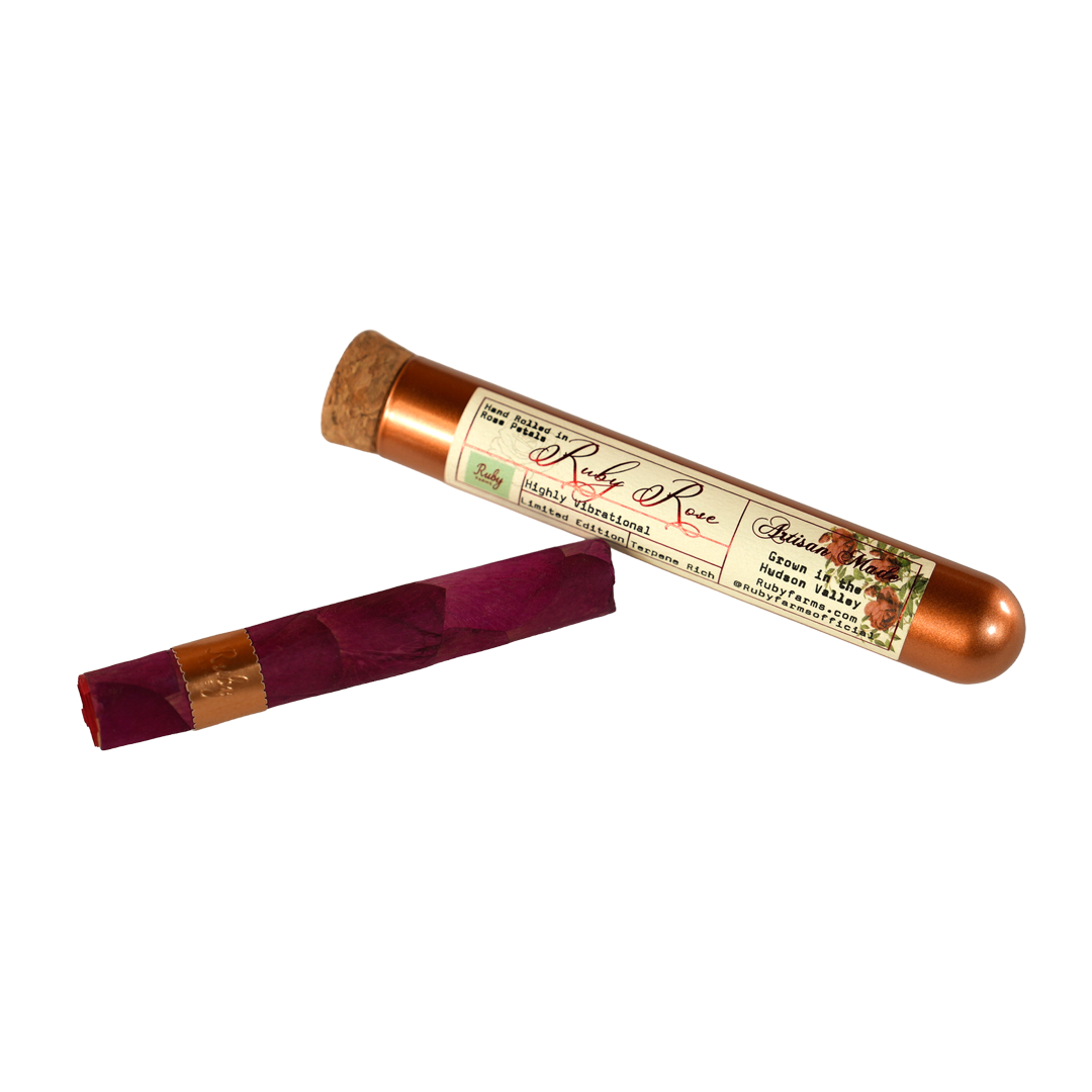 Glass tube labeled Ruby Rose strain and a deep red rolled item next to it on a white background.