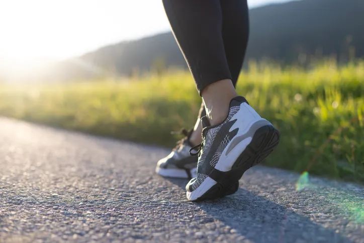A person taking a step forward on an outdoor path at sunrise, representing the momentum and direction that life coaching provides.