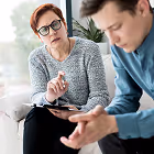 Counselor attentively listening to a man speaking during a therapy session in a bright room.