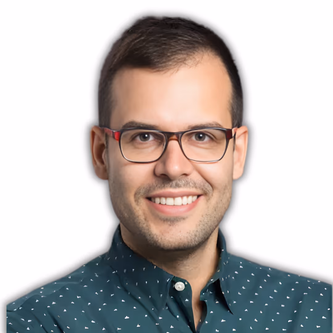 Smiling man with short brown hair and glasses wearing a beige button-up shirt with arms crossed.
