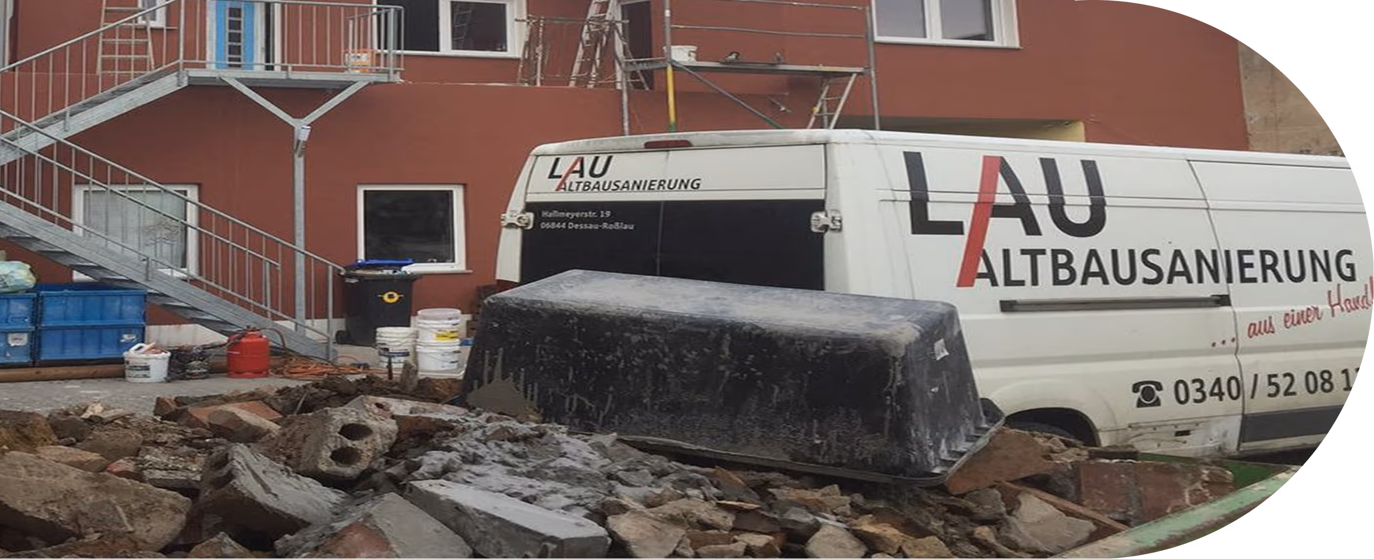 Bauzone mit Schutt und Bauschutt, einem weißen Transporter der Firma LAU Altbausanierung vor einem roten Gebäude mit Außentreppe.