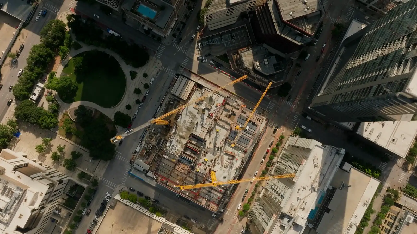 Aerial view of an active downtown Austin construction site with tower cranes