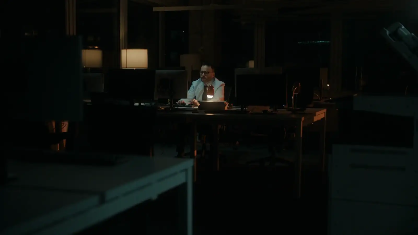 Developer working at a bright computer screen in a dark office