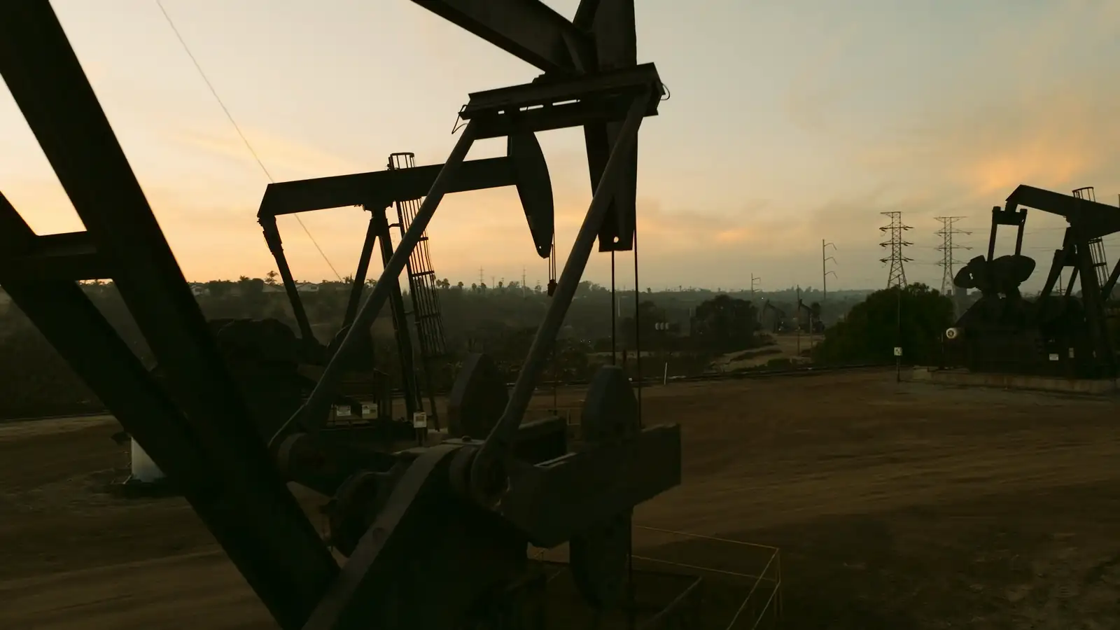 Pumpjack silhouetted against a sunset in an oil field